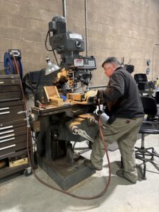 Photo of worker using the mill to work in a machine part